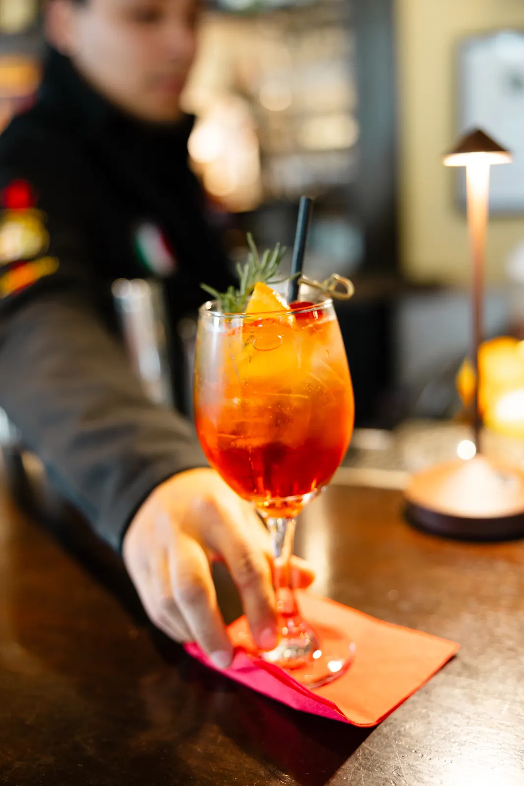 A spritz set down on the Downstairs Bar, the bartender behind it