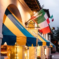 The blue and yellow awnings of Little Napoli on Dolores Street at dusk.