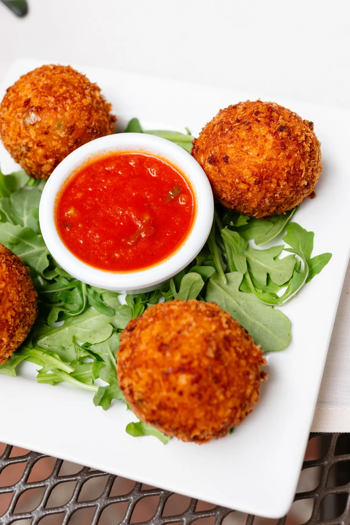 Arancini at Little Napoli: crispy saffron-risotto balls on arugula around a dish of marinara