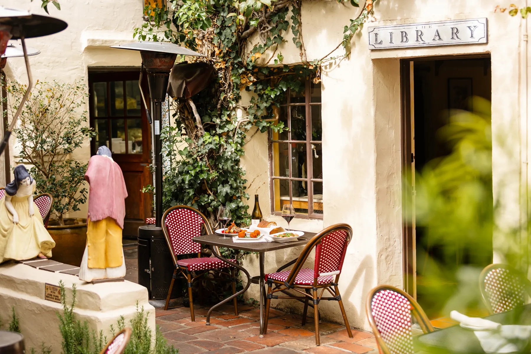 The door to The Library in the courtyard, with the LIBRARY sign above it and a cafe table outside
