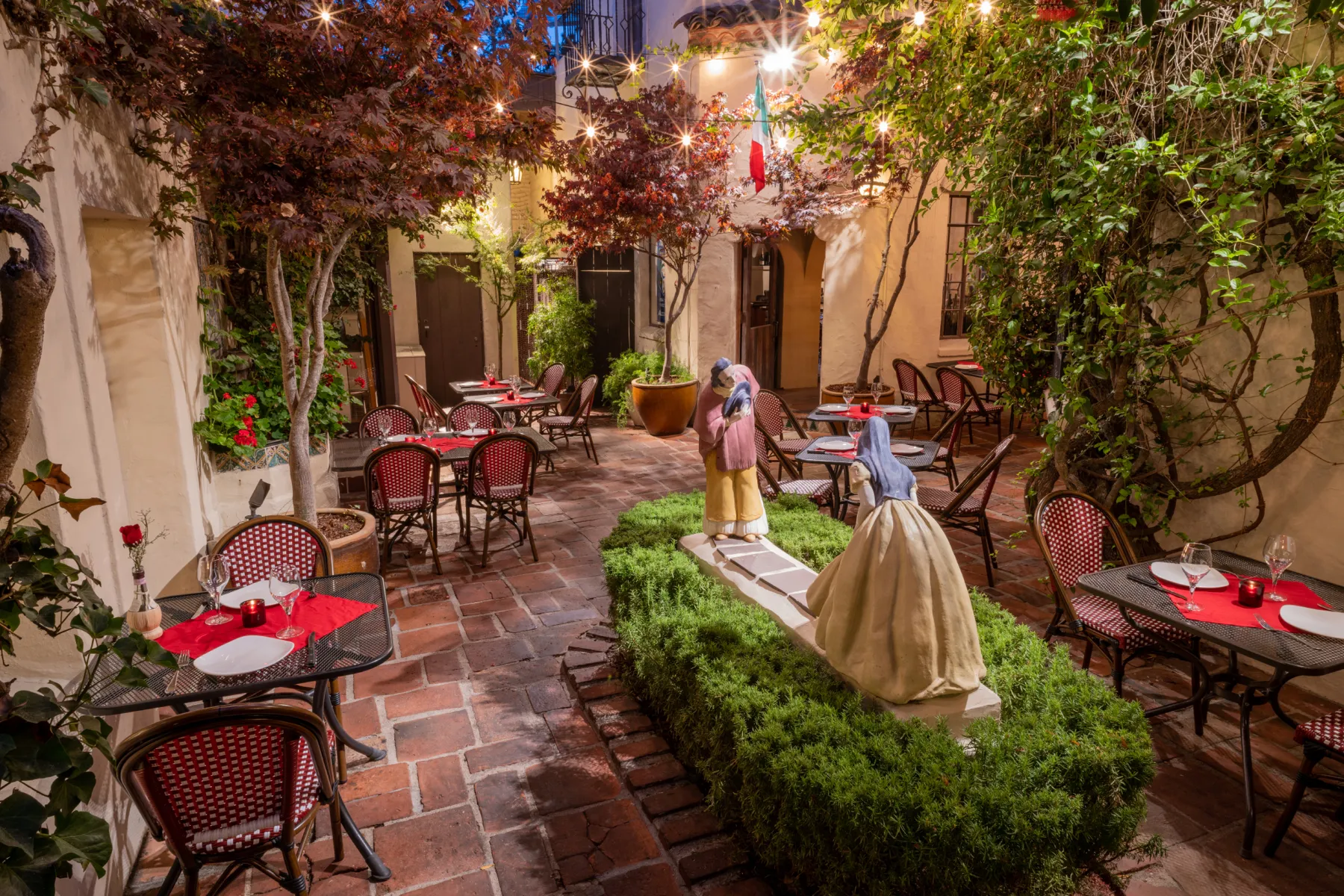 The Little Napoli courtyard with tables under the trees
