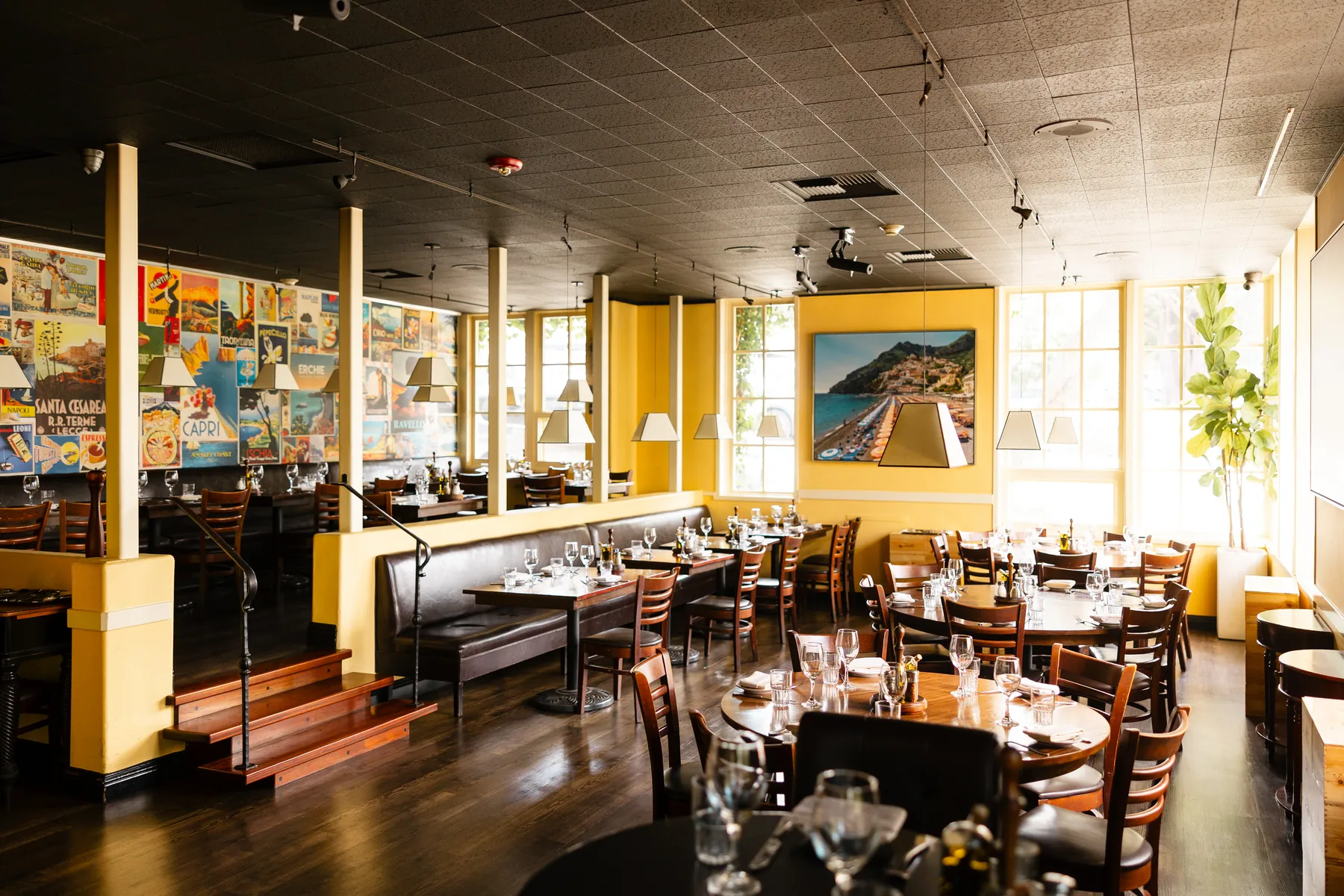 The Vesuvio dining room, tables set, yellow walls and vintage Italian posters
